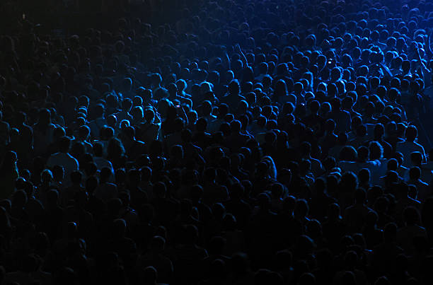 Dark background of crowd at concert Cheering crowd at the rock concert in a concert hall concert hall photos stock pictures, royalty-free photos & images