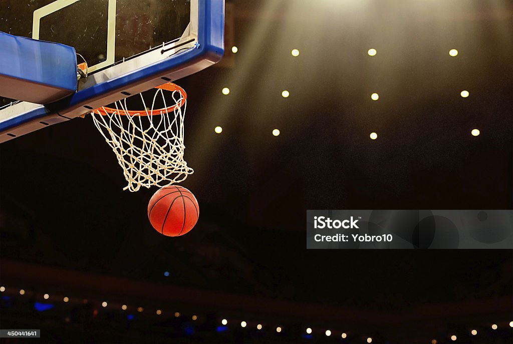 Basketball basket with ball going through net A ball swishes through the net at a basketball game in a professional arena Basketball - Sport Stock Photo