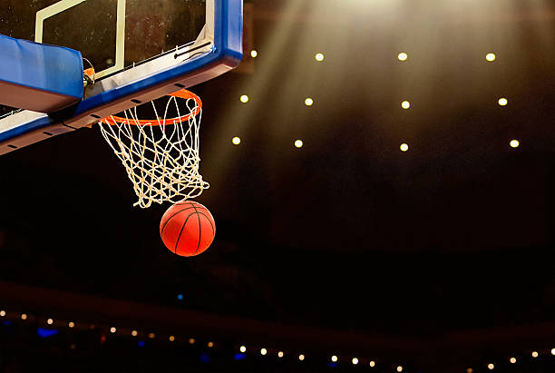 Basketball basket with ball going through net A ball swishes through the net at a basketball game in a professional arena basket stock pictures, royalty-free photos & images