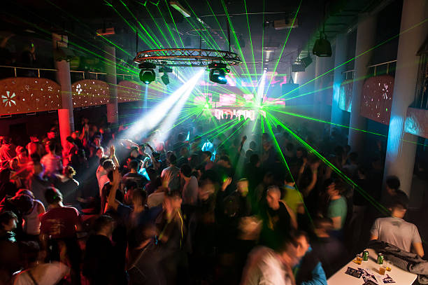 People dancing at a club with laser lights stock photo