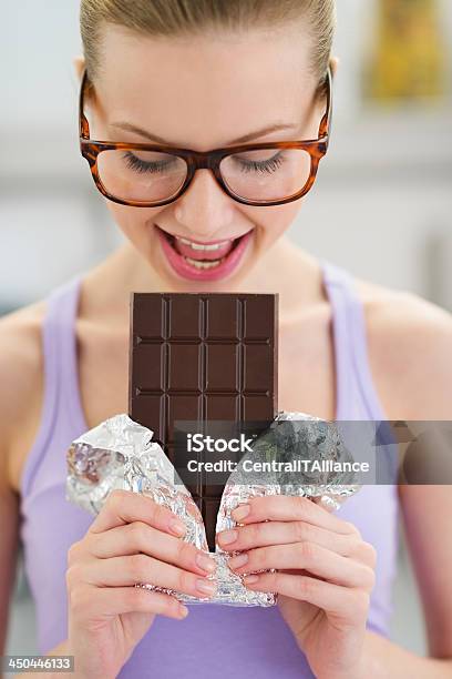 Young Girl Eating Chocolate Bar Stock Photo - Download Image Now - Women, Chocolate, Eyeglasses