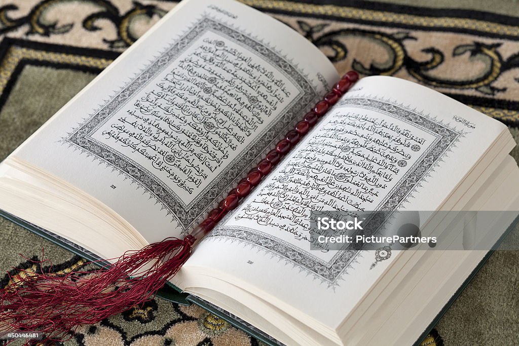 Koran and the prayer beads Koran and the prayer beads on a carpet Arabic Script Stock Photo