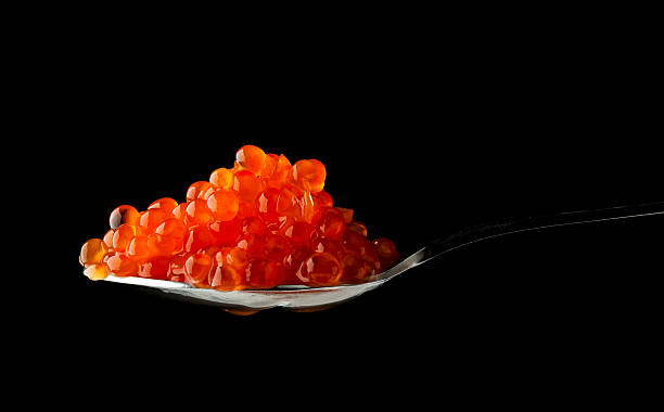 istock Red caviar in metal spoon isolated on black 450451505