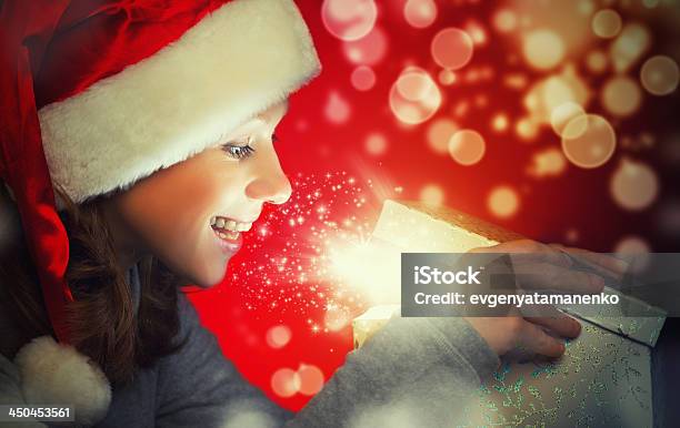 Foto de Feliz Mulher Em Um Boné De Natal Abre A Caixa Mágica e mais fotos de stock de Abrindo