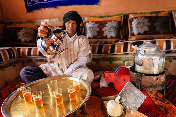 Moroccan man preparing Maghrebi mint tea. Maghrebi mint tea is a green tea with mint leaves. Tea occupies a very important place in Moroccan culture and is considered an art form.http://bem.2be.pl/IS/morocco_380.jpg berber stock pictures, royalty-free photos & images