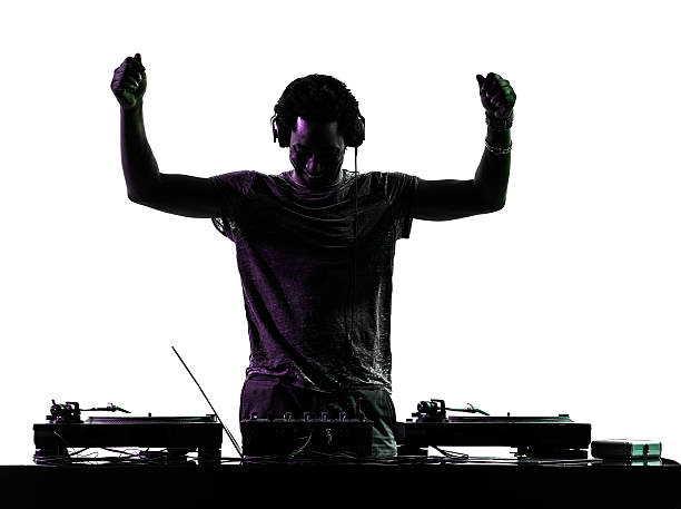 Silhouette of disc jockey raising arms over turntables stock photo