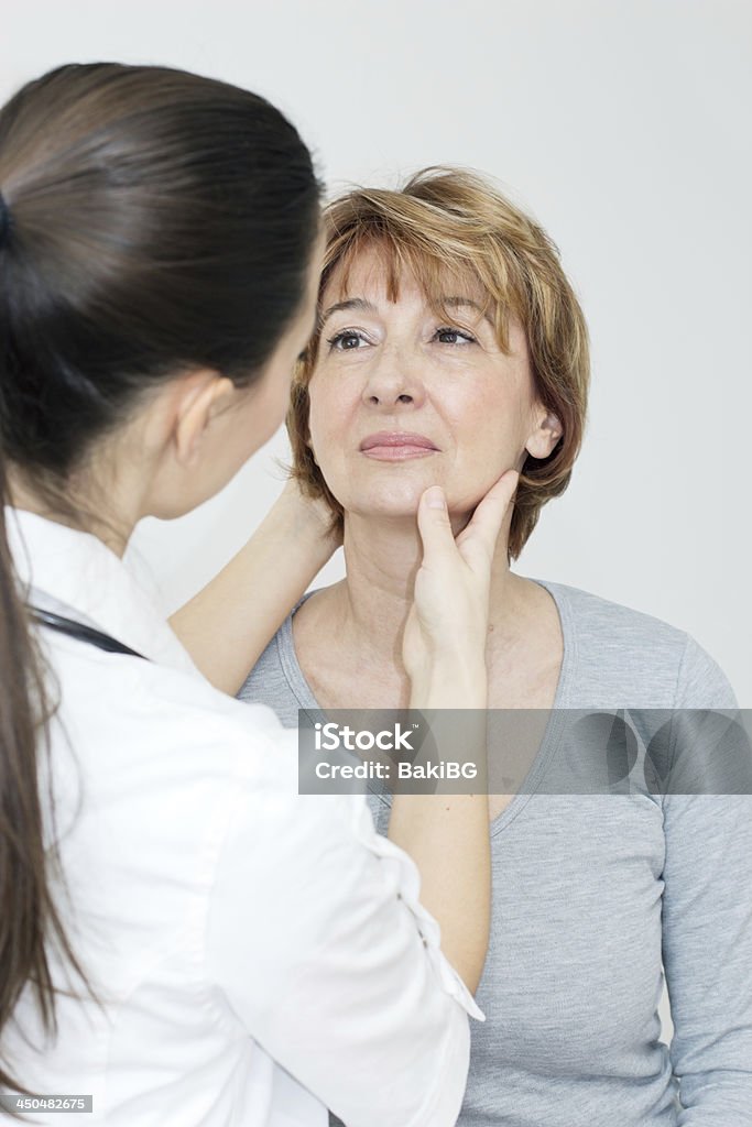 A female doctor examining a neck injury Young female doctor examining her patient. Patient Stock Photo