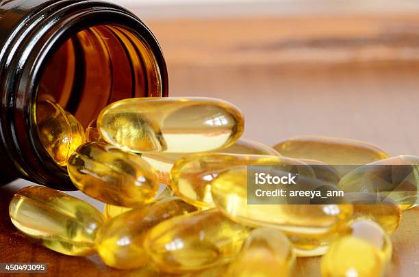 Yellow Transparent Capsules Falling Out Of A Brown Bottle Stock Photo - Download Image Now