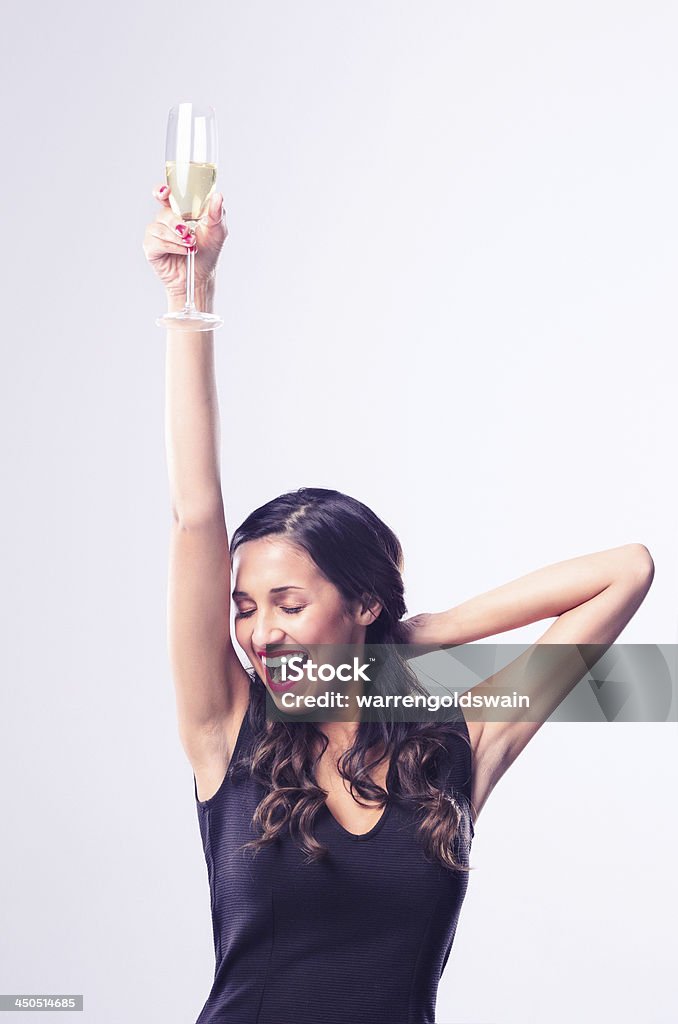 Glamourous woman holding glass of sparkling wine champagne Gorgeous glamourous woman dancing and enjoying herself while holding a glass of champagne, wearing a little black dress for new years eve party celebration Dancing Stock Photo