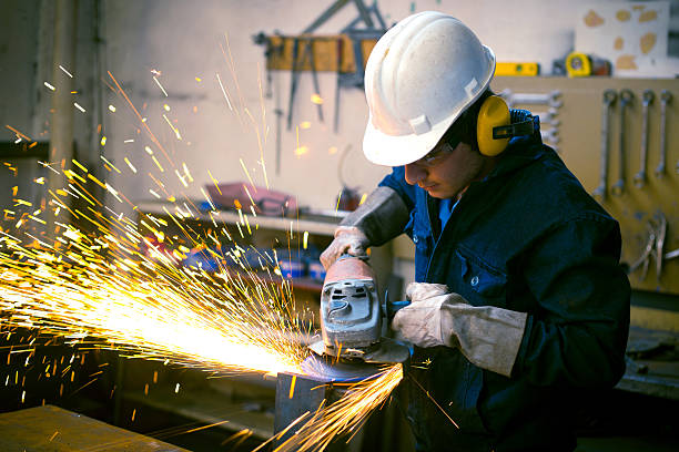 istock Worker wearing safety gear using grinder with sparks flying 450548017