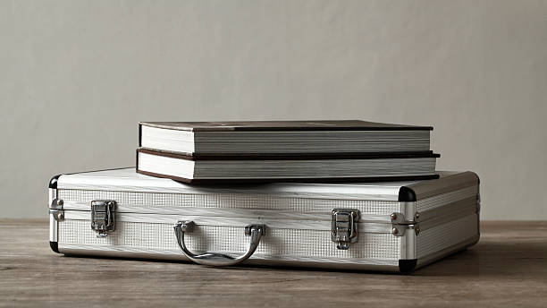 istock Books over aluminum suitcase on wooden table 450552249