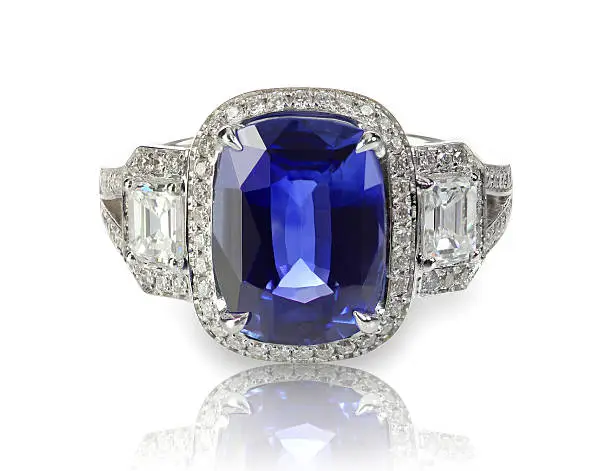 Blue tanzanite or sapphire precious gemstone and diamond ring isolated on white with a reflection