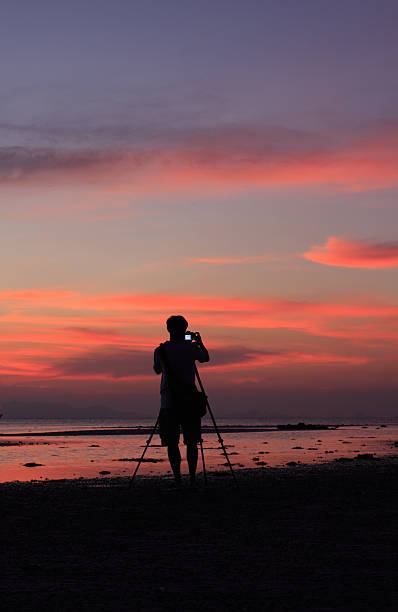 istock photographer silhouette by the beach at dusk 450592629