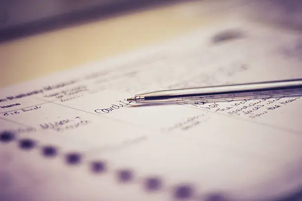 Selective focus on a pen lying on a guestbook with handwritten comments