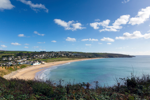 Praa Sands Cornwall England near Penzance and Mullion on the South West Coast Path with sandy beach and blue sky and white fluffy clouds on a beautiful sunny day