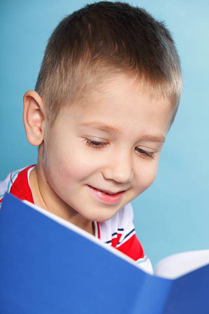 istock child boy kid reading a book on blue 450603179