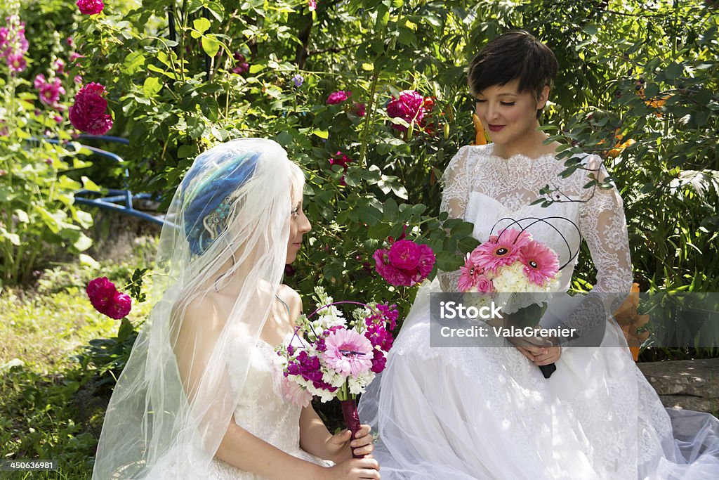 Dwa uśmiechnięte brides siedzi w ogrodzie różanym. - Zbiór zdjęć royalty-free (20-24 lata)