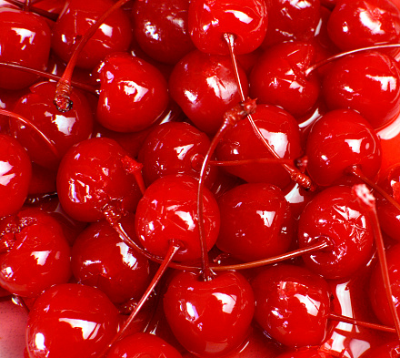 Festive background of red cocktail maraschino cherries with stems.