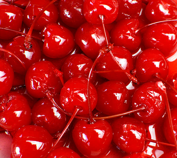 Close-up of glossy red maraschino cherries with stems Festive background of red cocktail maraschino cherries with stems. maraschino cherry stock pictures, royalty-free photos & images