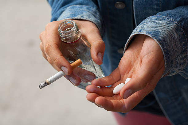 девоч�ка держит водку, таблетки и сигарет - smoking smoking issues cigarette addiction стоковые фото и изображения