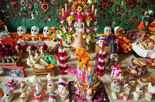 Mexican sugar skulls and skeletons on a traditional Dia de Muertos table