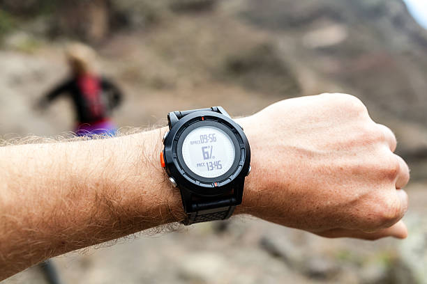 Runner on mountain trail looking at sportwatch, checking performance or heart rate pulse. Sport and fitness outdoors in nature.