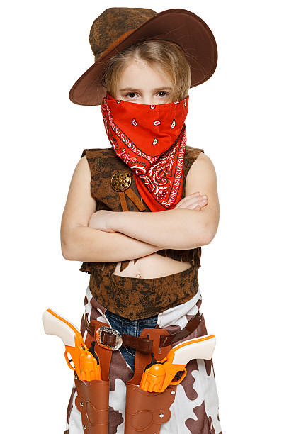 A cute little boy dressed in western-themed attire showing a gun gesture while at home