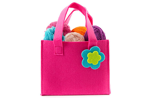 balls of yarn in a pink handbag isolated on white