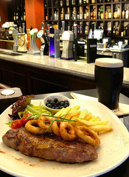 Steak and a Pint of Dark Beer Garnished steak with a pint of dark beer in a bar guinness photos stock pictures, royalty-free photos & images