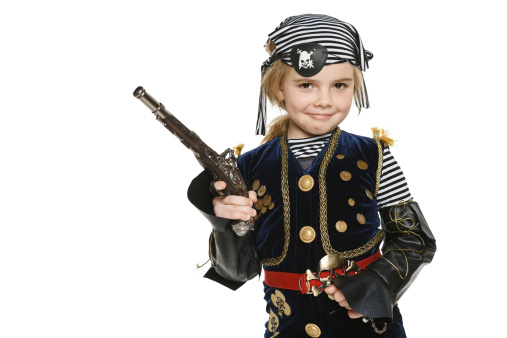 Little girl wearing pirate costume holding a gun, over white background