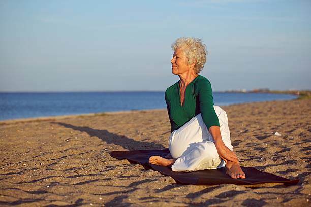 istock Senior woman performing a yoga routine on the beach 450850351
