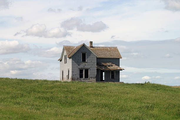 istock Abandoned, isolated home on grassy plain against cloudy sky 450852683