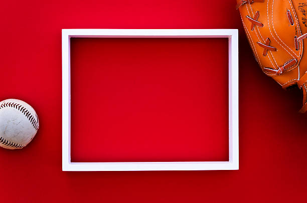 empty picture frame on a red wall with baseball equipment stock photo