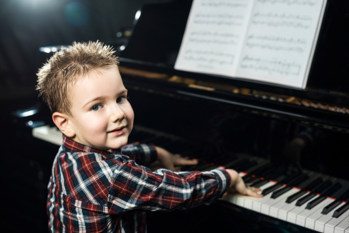Little boy learning to play the piano.