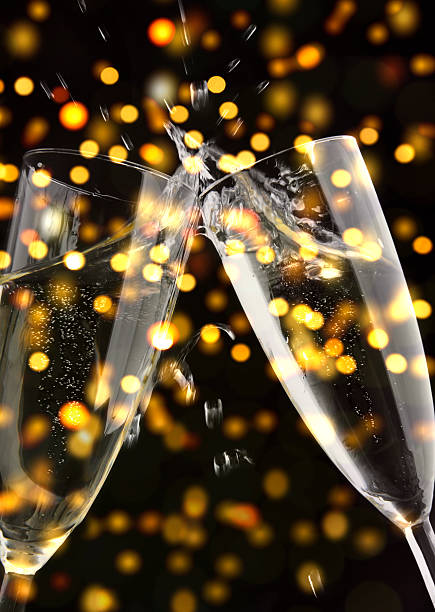istock Champagne toast, two glasses with splash, sparkling lights in background 450874727
