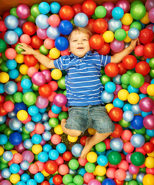 istock Happy young boy playing in a pit of colorful plastic balls 450876415