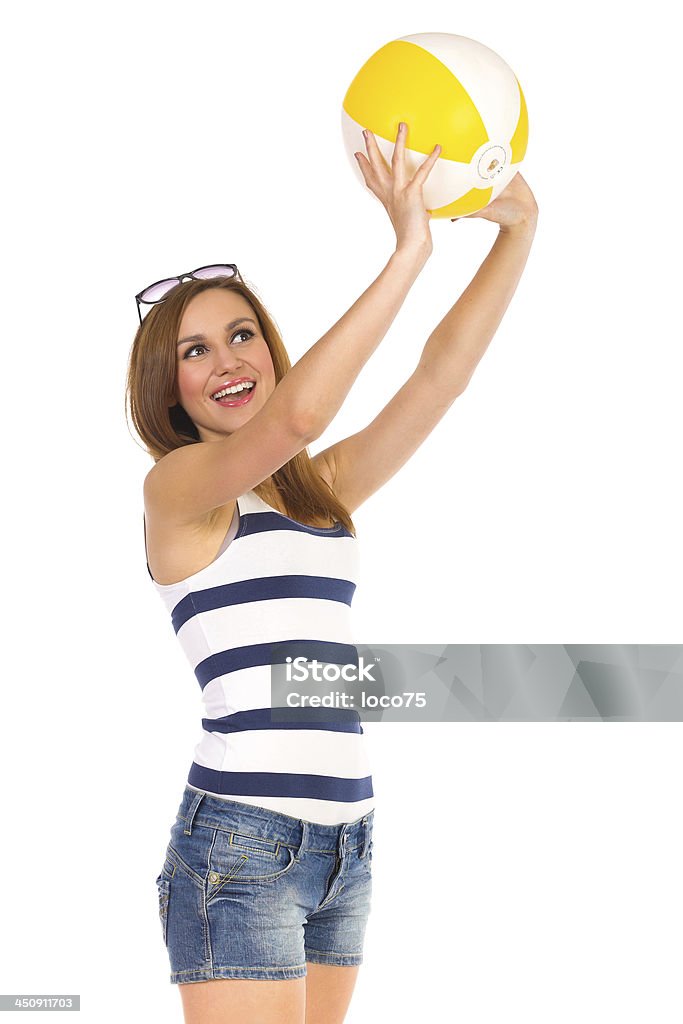 Smiling young woman playing with a beach ball. Smiling young woman playing with a beach ball. Three quarter length studio shot isolated on white. Holding Stock Photo