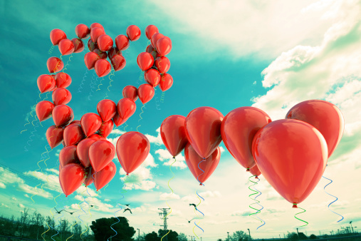 Red balloons forming  a heart shape over the sky