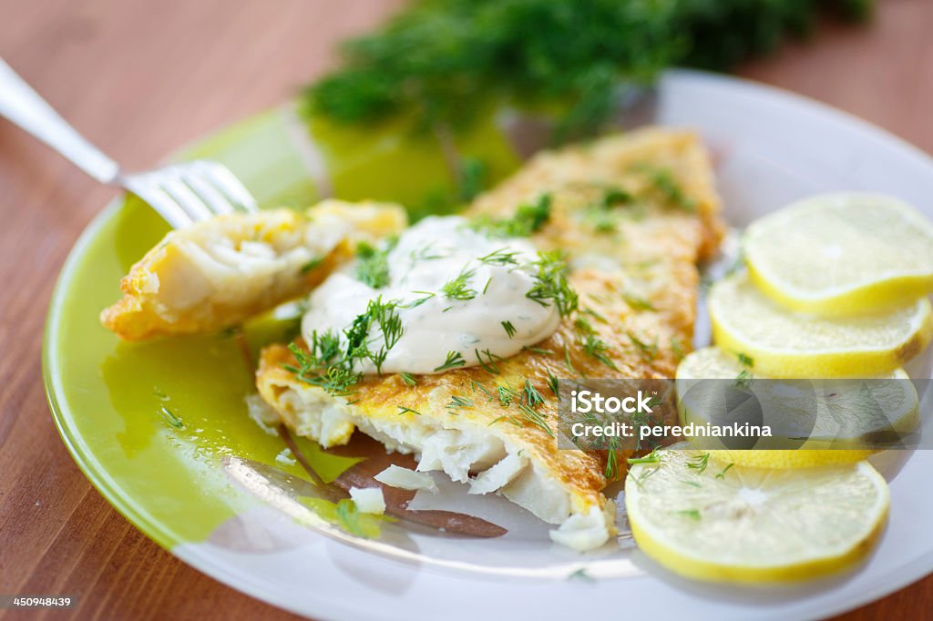 Fried fish with sliced lemons on the side fried fish with sauce and lemon on a plate Tilapia Stock Photo