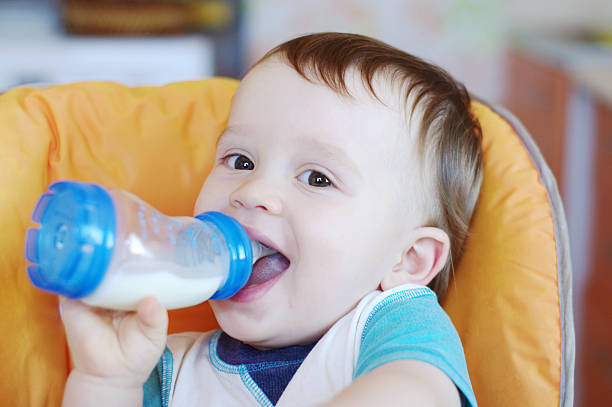 istock smiling baby drinks milk from a small bottle 450974233