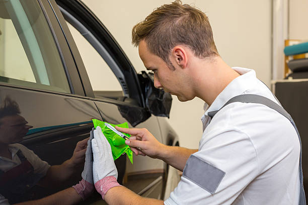 istock Car wrapping specialist cutting adhesive foil with a box cutter 450974813