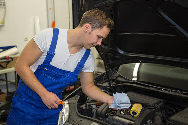 istock Mechanic in garage checking motor oil level at a car 450974873