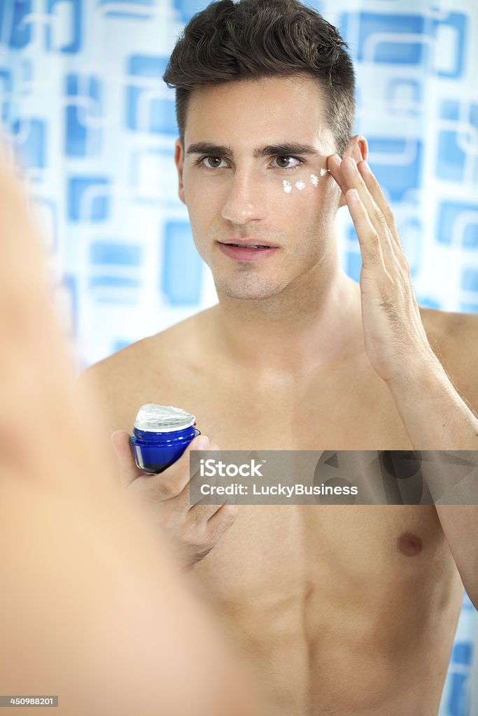handsome man  applying cream on face Young handsome man  with healthy skin applying cream Adult Stock Photo