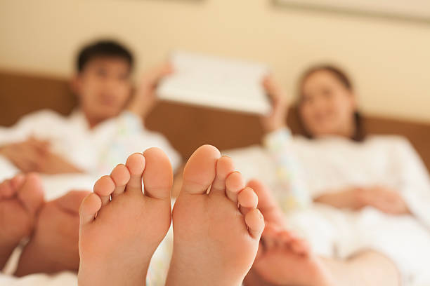 Family in Bed with Bare Feet Family in Bed with Bare Feet bed human foot couple two parent family stock pictures, royalty-free photos & images