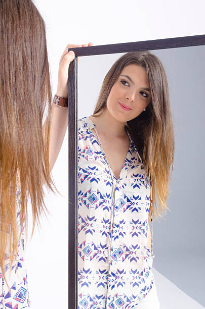 istock real young woman looking in a mirror 451015651