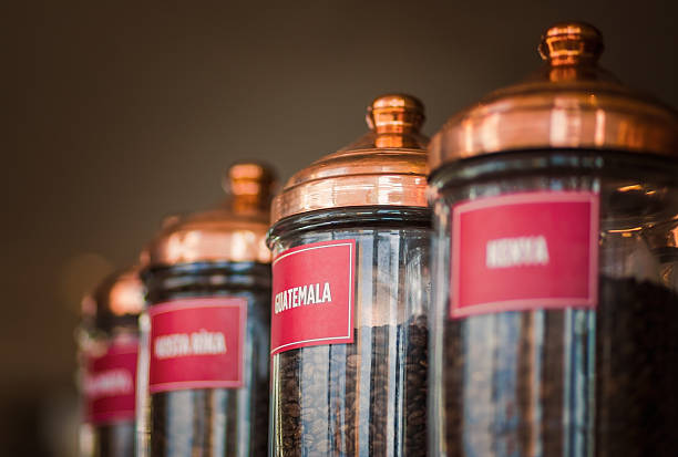 Fresh, roasted coffee beans in small jar and placed  on green wooden desk on blured indoor background