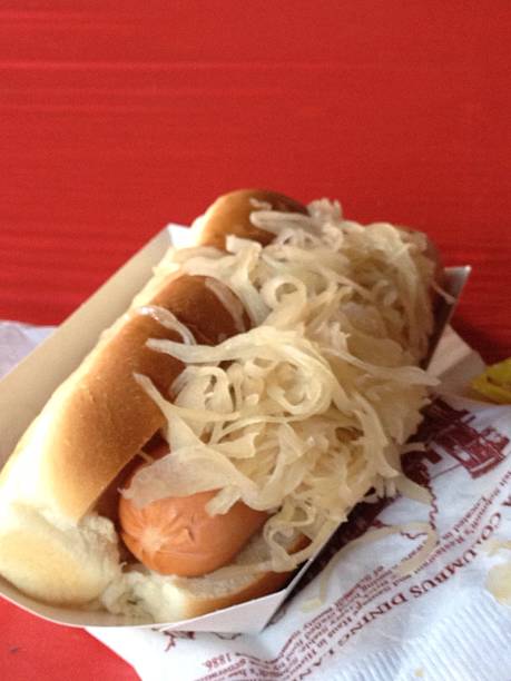 Beer Fest typical german hot dog with sausage, yellow mustard, sauerkraut in wooden emsa and dark background