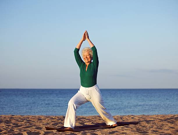 istock Senior woman stretching against beach background 451055547