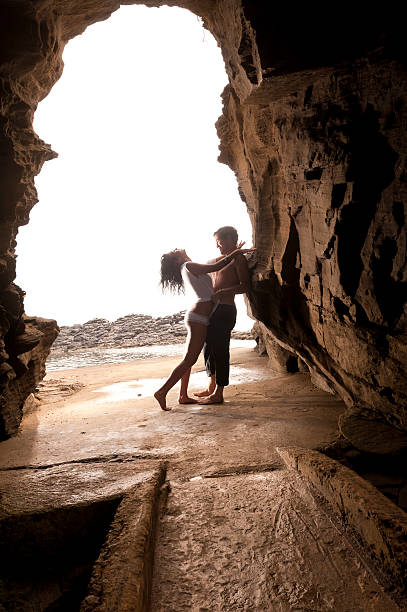 Young attractive couple leaning on rock archway stock photo