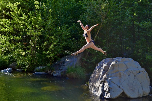 Woman leaping with joy of life, joie de vivre, into water, action shot